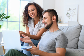 Fototapeta premium Young couple with gadgets relaxing on sofa at home