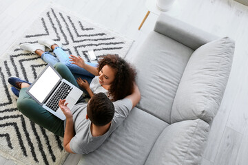 Young couple with laptop relaxing on sofa at home