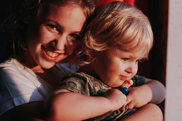 Close up portrait of siblings, sister and brother in sunset light. Shadows on the faces. Love, happines, family, childhood concept.