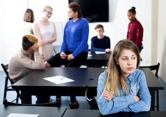 Pretty new girl student being shy among classmates at recess in school