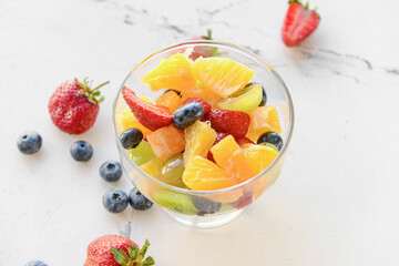 Glass with fruit salad on light background