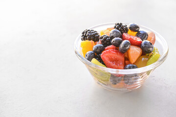 Bowl with fruit salad on light background