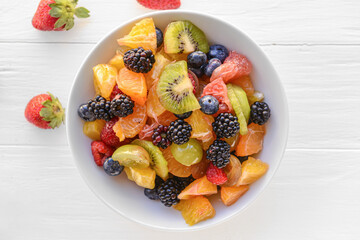 Bowl with fruit salad on light background