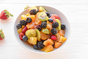 Bowl with fruit salad on light background