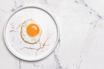 Plate with tasty fried egg on light background