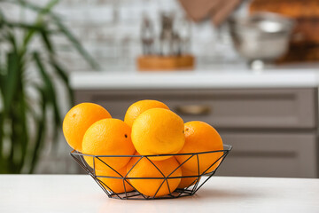 Basket with juicy oranges on kitchen table