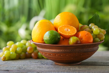 Bowl with different fruits on table outdoors