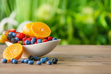 Bowl with different fruits and berries on table outdoors