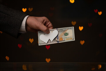 Man hand holds bill and hearts made of paper