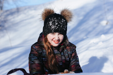 Fototapeta na wymiar A cute ten years old girl having fun on a winter day outdoors. Wintertime, entertainment, activity, childhood, holidays, christmas concept. 