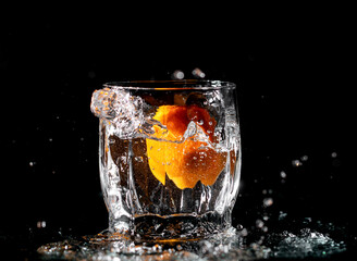 tangerine in water with splashes on black background