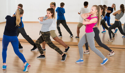 Fototapeta na wymiar Group of positive smiling european teenagers dancing in classroom
