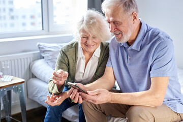 senior couple looking at children's photos in smartphone, online surfung Net,modern technology...