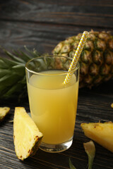 Ripe pineapple and glass of juice on wooden background