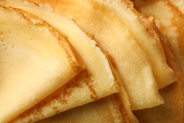 Delicious thin pancakes on whole background, close up