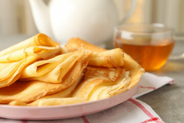 Tea, and plate of thin pancakes on gray table