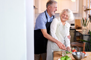 Fototapeta na wymiar elderly couple carving vegetables together, handsomegray haired man help wife to cook