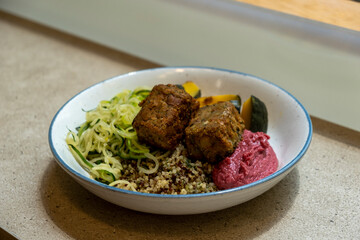 Vegan lunch bowl, featuring Zucchini Noodles, Quinoa, Falafel, Beetroot Hummus and roasted Pumpkin. Stock Photo.