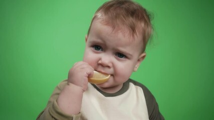One Cute Beautiful Baby Eating a Lemon. A Child Tastes the Raw Lemon. Tiny Playful Boy Eats Fruits. Young Kid Holding Eat Tasty. Fun Expression Emotion Faces Kids from Eating Sour Lemon. Bright Look