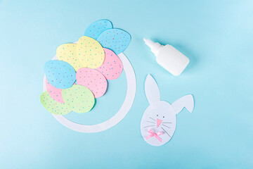 DIY and kids creativity. Step by step instruction: how to make paper easter wreath. Step7 decorate paper bunny with ears, nose and bow. Childrens handmade Easter craft.