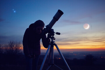 Woman looking at night sky with amateur astronomical telescope.