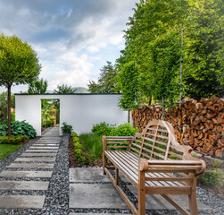 Piękny nowoczesny ogród z klasyczną drewnianą ławką i nowoczesną architekturą ogrodową