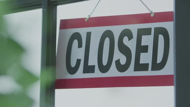 An open sign in the window of a business is flipped to the side labeled closed