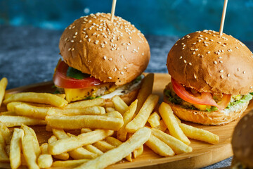 Cheeseburgers with fry potato on the wooden board