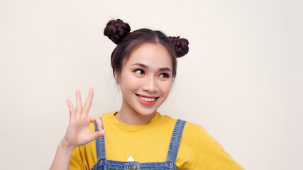 Flying start! Fabulous girl with splendid smile on her face in front of white background is showing “OK” sign with her elegant hand.