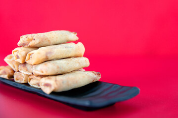 A plate of fried spring rolls at the beginning of spring on a red background