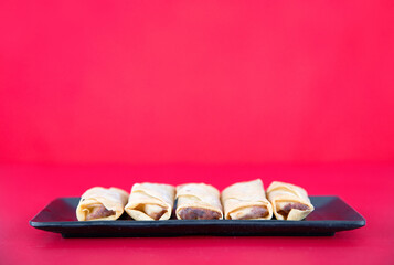 A plate of fried spring rolls at the beginning of spring on a red background