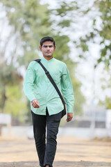 Young Indian male model standing and holding the office bag and giving expression.