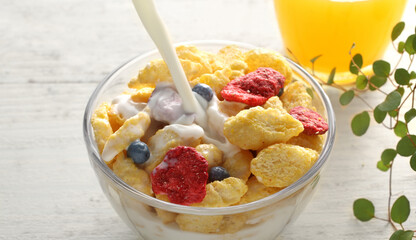 ミルクを注いでいる朝食のシリアルやフレーク