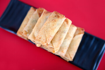Overlooking a dish of fried spring rolls on a red background