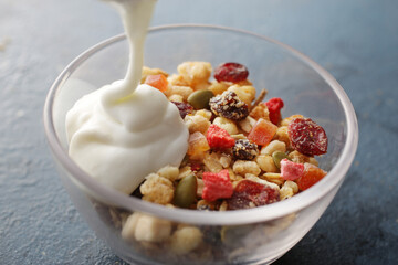 ヨーグルトを注いでいる朝食のフルーツグラノーラ