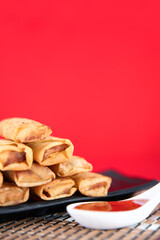 Fried spring rolls and dips on a red background