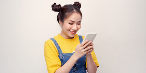 Portrait if a shocked young girl in dress looking at mobile phone isolated over white background