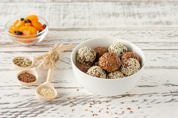 Homemade Healthy Paleo Raw Energy Balls with Nuts, coconut flakes and Dates on a white plate with ingridients