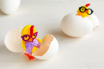 Chicken toys in glasses with a bow. Chick with egg shells