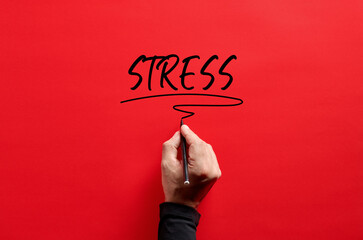 Male hand writing the word stress on red background.