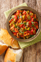 Taktouka is a traditional Moroccan salad composed of tomatoes, bell peppers, garlic, toasted paprika and olive oil closeup in the plate on the table. Vertical top view from above