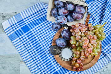 Fresh plums and a bunch of grapes on a tablecloth