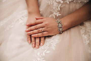Beautiful well-groomed female hands on the background of a white dress 