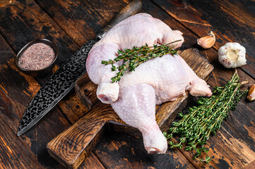 Raw chicken legs on a cutting board. Dark wooden background. Top view