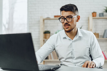 Young successful businessman using laptop at his office desk
