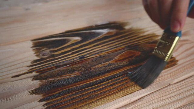 Hand in a glove paints a beautiful textured wood with a brush
