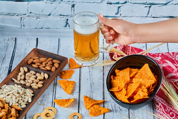 Assorted snacks, chips, and beer on blue table. Table for group of friends
