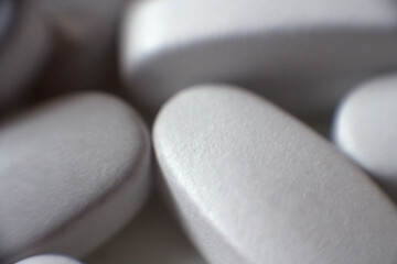 Tablets piled closely together. White pills close up.
