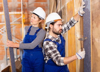 Two professional builders insulate walls inside the house. High quality photo