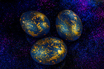 Abstract photo of eggs on galaxy glitter dark background. Easter cosmic space colored eggs. Idea for greetings and Easter. Top view concept with colored eggs in flat lay style.